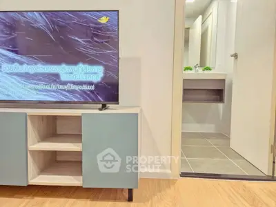 Modern living room with sleek TV stand and glimpse of bathroom, showcasing contemporary design.