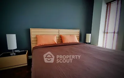 Modern bedroom with stylish decor and natural light, featuring a comfortable bed and elegant lamps.