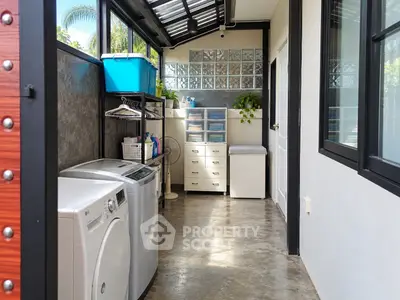 Modern laundry room with washing machine and storage cabinets in a bright, airy space.
