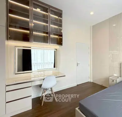 Modern bedroom with sleek built-in desk and storage, featuring elegant lighting and wooden flooring.