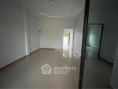Spacious empty room with glossy tiled flooring and natural light, ideal for customization.