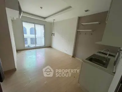Spacious unfurnished apartment with modern kitchen and large window for natural light.