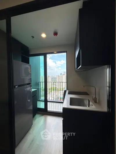 Modern kitchen with city view and balcony access in high-rise apartment