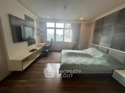 Spacious bedroom with city view, modern decor, and built-in desk area.