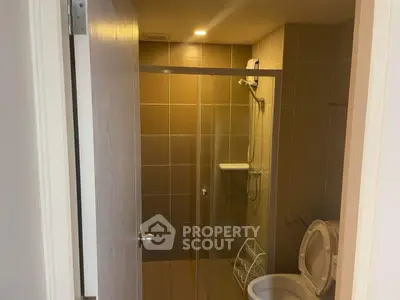 Modern bathroom with glass shower and washing machine in compact space.