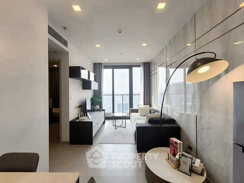 Modern living room with stylish decor and city view, featuring sleek furniture and ambient lighting.