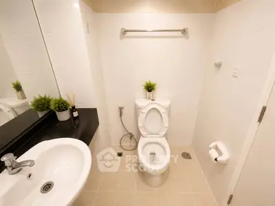 Modern bathroom with sleek fixtures and minimalist design, featuring a white toilet and sink.