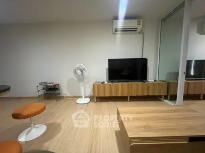 Modern living room with wooden flooring, stylish furniture, and air conditioning unit.