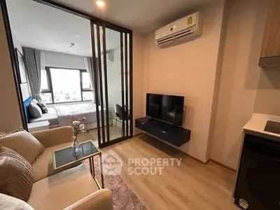 Modern apartment interior with cozy living room and stylish bedroom separated by glass partition.