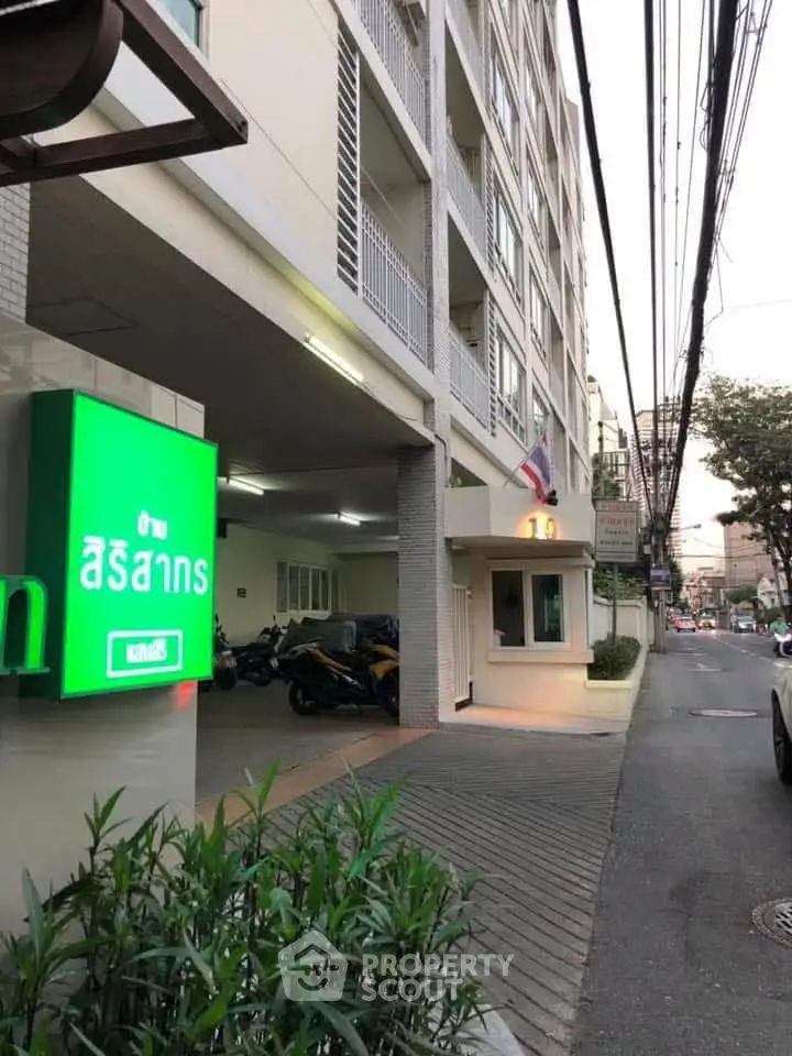 Modern apartment building exterior with parking area and street view.