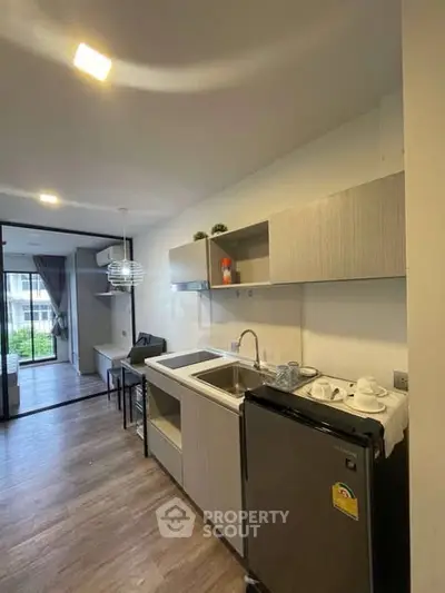 Modern open-layout kitchen with sleek cabinetry and compact appliances in a stylish apartment.