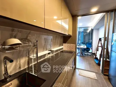 Modern kitchen with sleek design and open layout leading to a study area.