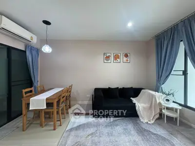 Modern living room with stylish decor and dining area, featuring a cozy black sofa and elegant lighting.