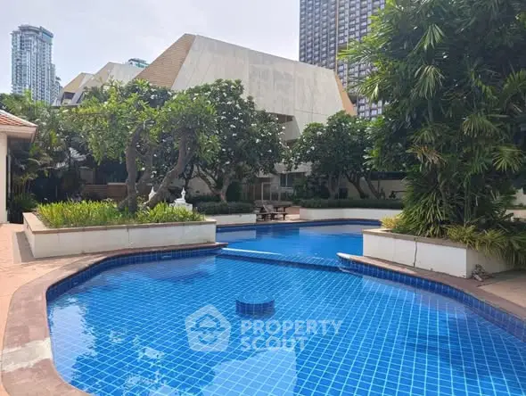 Luxurious residential pool area with lush greenery and modern architecture.