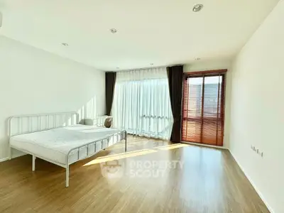 Spacious minimalist bedroom with natural light and wooden flooring