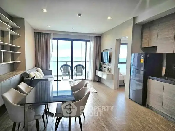 Modern living room with dining area and ocean view balcony in luxury apartment.