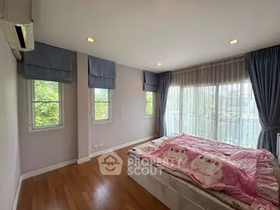 Charming bedroom with large windows and cozy decor, perfect for relaxation.