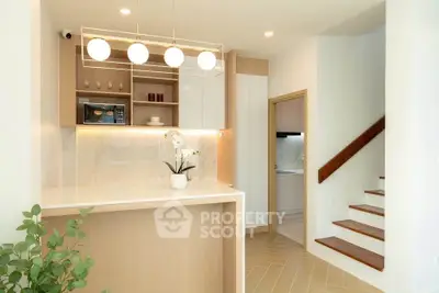 Modern kitchen with open layout and stylish lighting, featuring a sleek staircase and elegant decor.