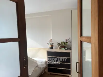 Cozy bedroom with natural light, featuring a bed, dresser, and indoor plants for a serene atmosphere.