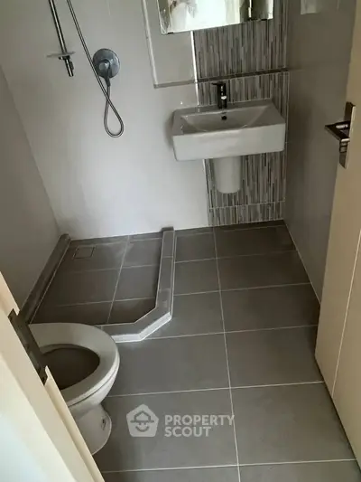 Modern bathroom with sleek fixtures and minimalist design, featuring a walk-in shower and contemporary sink.