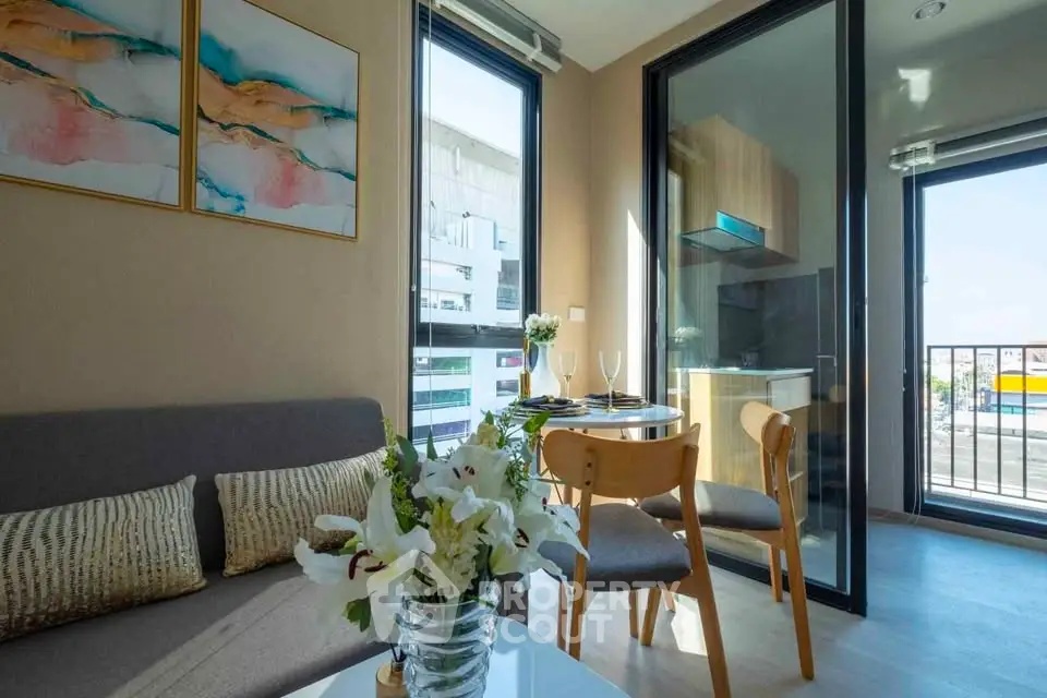 Modern living room with balcony and dining area, featuring stylish decor and natural light.