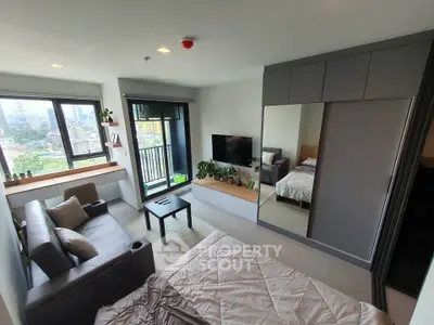 Modern studio apartment with cozy living area and city view balcony.