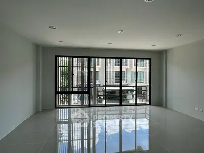 Spacious modern living room with large windows and city view, perfect for urban living.