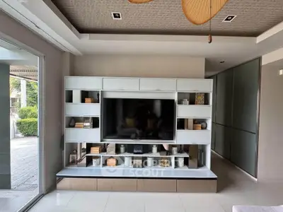 Modern living room with sleek entertainment center and large TV, featuring stylish shelving and contemporary decor.
