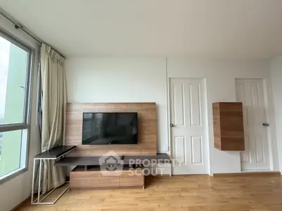 Spacious living room with modern TV setup and wooden flooring