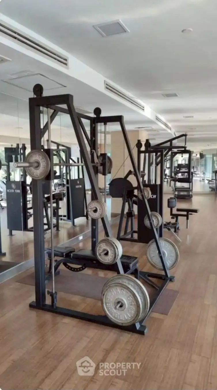 Spacious gym with modern fitness equipment and mirrored walls in luxury real estate property.