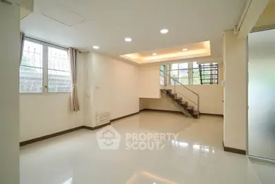 Spacious modern living room with staircase and large windows, perfect for natural light.