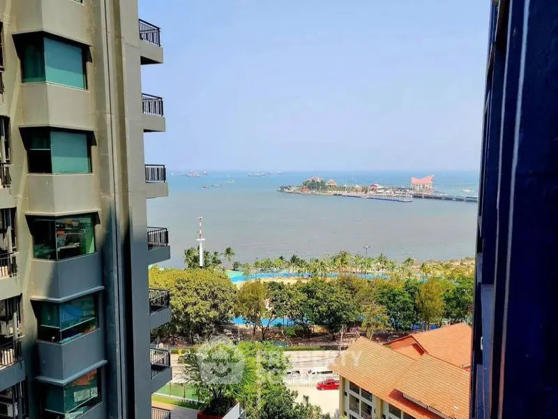 Stunning ocean view from high-rise apartment with lush greenery and clear blue skies.