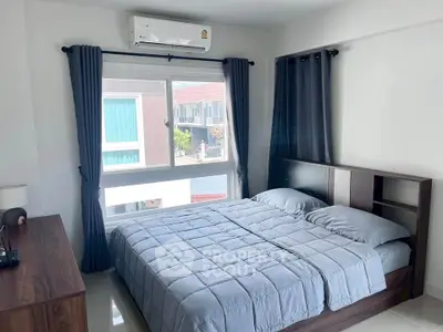 Modern bedroom with large window and stylish furnishings in a bright apartment.