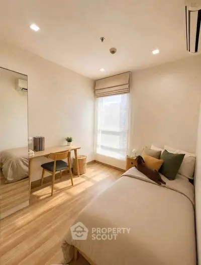 Cozy bedroom with natural light, wooden flooring, and minimalist decor, perfect for relaxation and comfort.