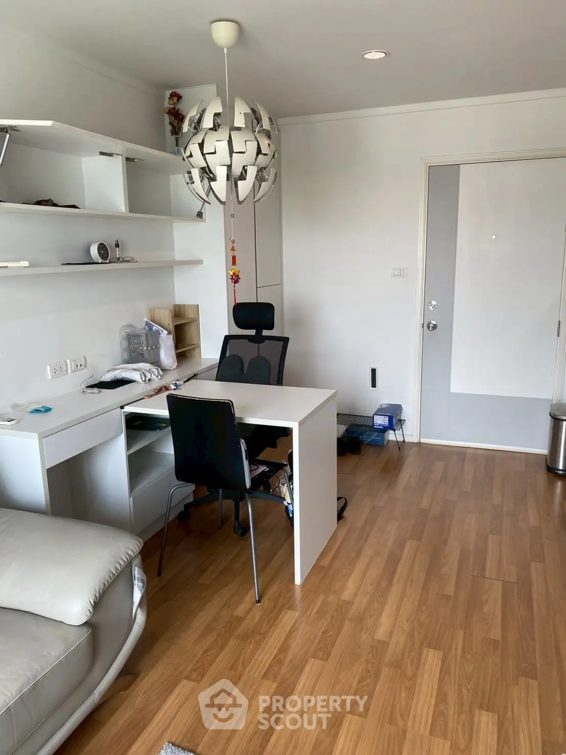 Modern study room with sleek desk and chair, stylish shelving, and contemporary lighting in a cozy apartment.