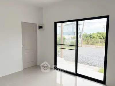 Bright room with large window and door overlooking a garden, perfect for modern living.