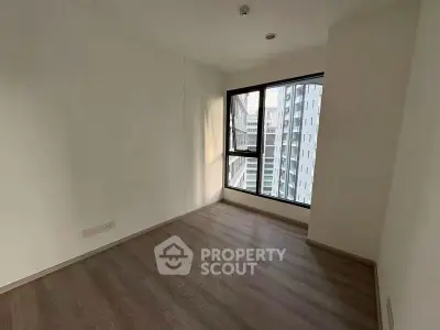 Spacious empty room with large window and city view, perfect for customization.