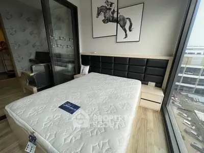 Modern bedroom with large windows and stylish decor, featuring a comfortable bed and elegant artwork.
