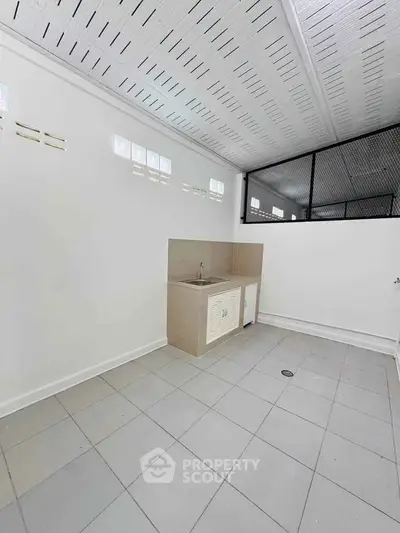 Spacious utility area with tiled flooring and modern sink, perfect for laundry or storage needs.