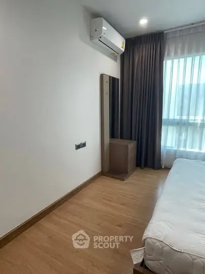 Modern bedroom with wooden flooring, air conditioning, and natural light from large window.