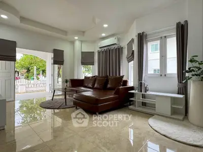Spacious living room with modern decor and large windows offering natural light and garden view.