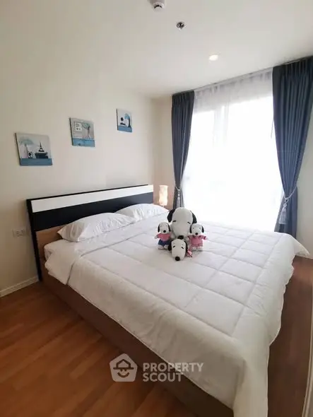 Cozy bedroom with large bed, plush toys, and natural light from window.