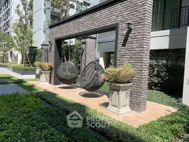 Modern garden area with stylish seating and lush greenery in a residential complex.