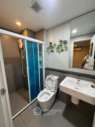 Modern bathroom with shower, toilet, and stylish decor in a contemporary apartment.