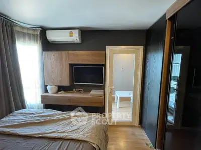 Modern bedroom with sleek design, featuring a wall-mounted TV, air conditioning, and stylish wooden accents.