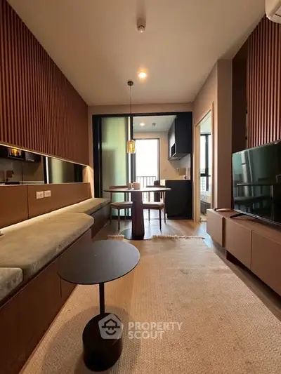 Modern living room with stylish decor and open kitchen layout, featuring elegant wooden accents and cozy seating.