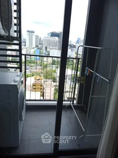 Modern balcony with city view, featuring washing machine and drying rack, ideal for urban living.