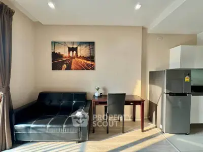 Modern living room with sleek black sofa, stylish artwork, and compact dining area.