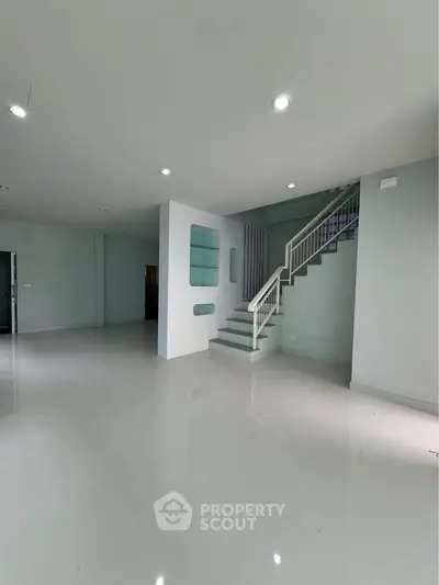 Spacious modern interior with sleek staircase and glossy floors, ideal for contemporary living.