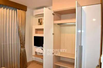 Modern bedroom with built-in wardrobe and wall-mounted TV, featuring elegant curtains and air conditioning.